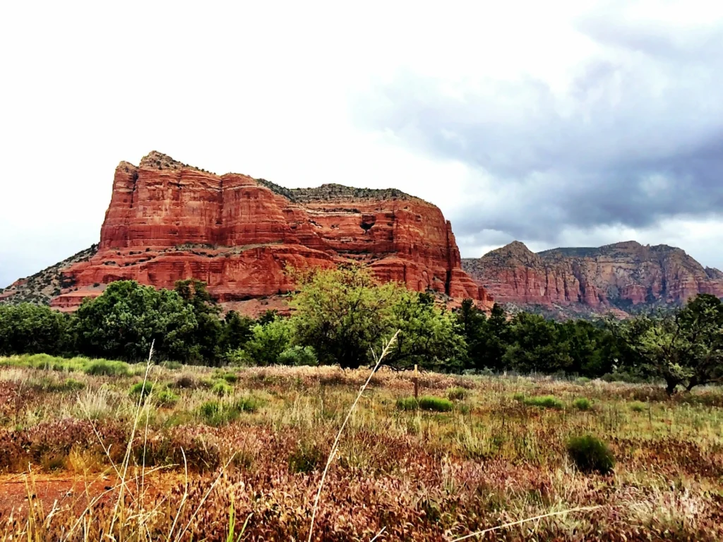 Hiker sitting on a red rock ledge at the Bell Rock vortex site in Sedona.