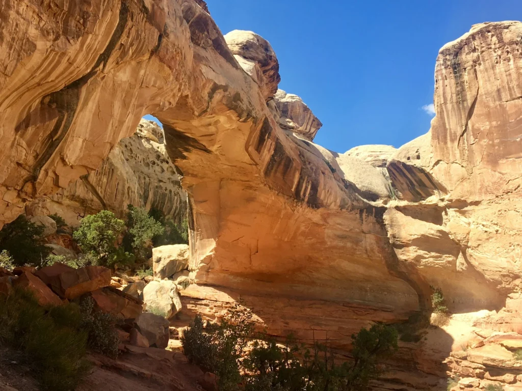 Huge hidden sandstone arch in Fay Canyon with hikers underneath for scale. Best Easy Hikes in Sedona.