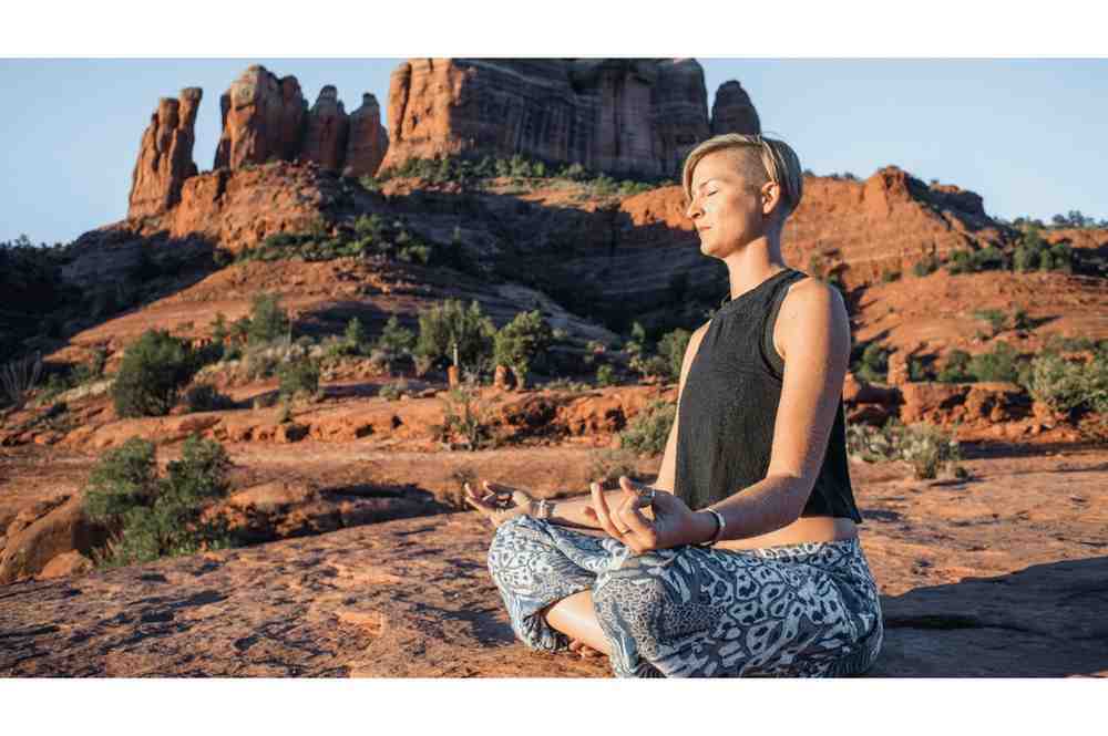 A hiker meditating on the red rocks at the Airport Mesa vortex site in Sedona. Airport Mesa Trail Sedona