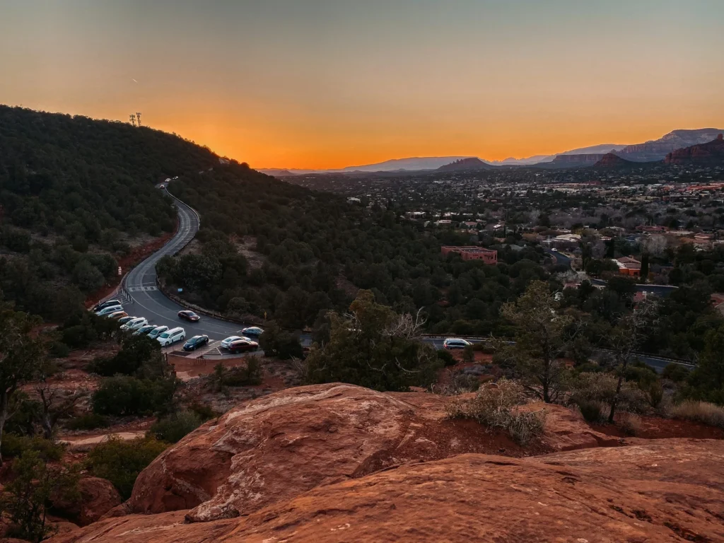 Crowded parking lot at a Sedona trailhead with a Red Rock Pass on the dashboard.