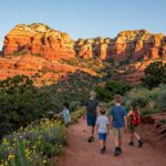 A hiker looking at the glowing red rocks of Cathedral Rock during sunset in Sedona. Sedona Vortex & Spiritual Hiking Guide