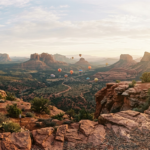Hot air balloons floating over Sedona red rocks at sunrise from Airport Mesa Trail.
