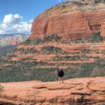 The sun setting over Bell Rock Pathway in Sedona Arizona with a hiker on the trail.