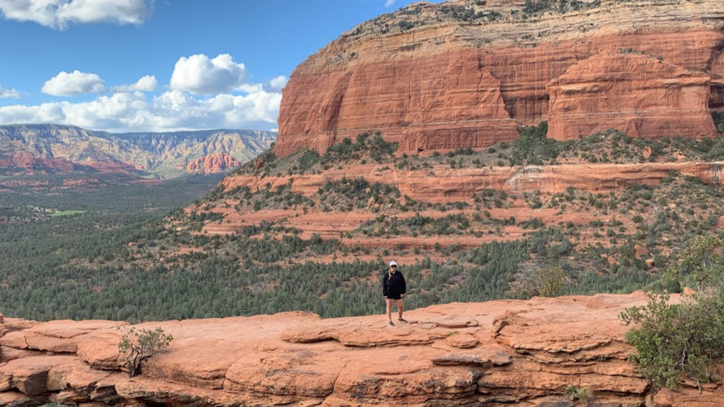 The sun setting over Bell Rock Pathway in Sedona Arizona with a hiker on the trail.