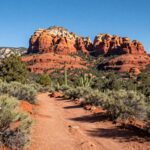 A hiker on the Courthouse Butte Loop Trail in Sedona at sunset with red rock views.
