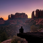 A traveler overlooks a scenic red rock valley in Sedona during a vibrant sunset. Sedona Easy Hike Itineraries