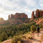 A hiker overlooks the red rock spires of the Soldier Pass trail Sedona during sunrise.
